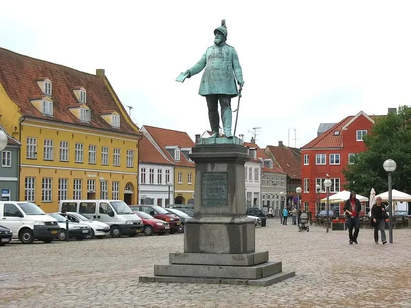 Statue in cobblestone town square with colorful buildings