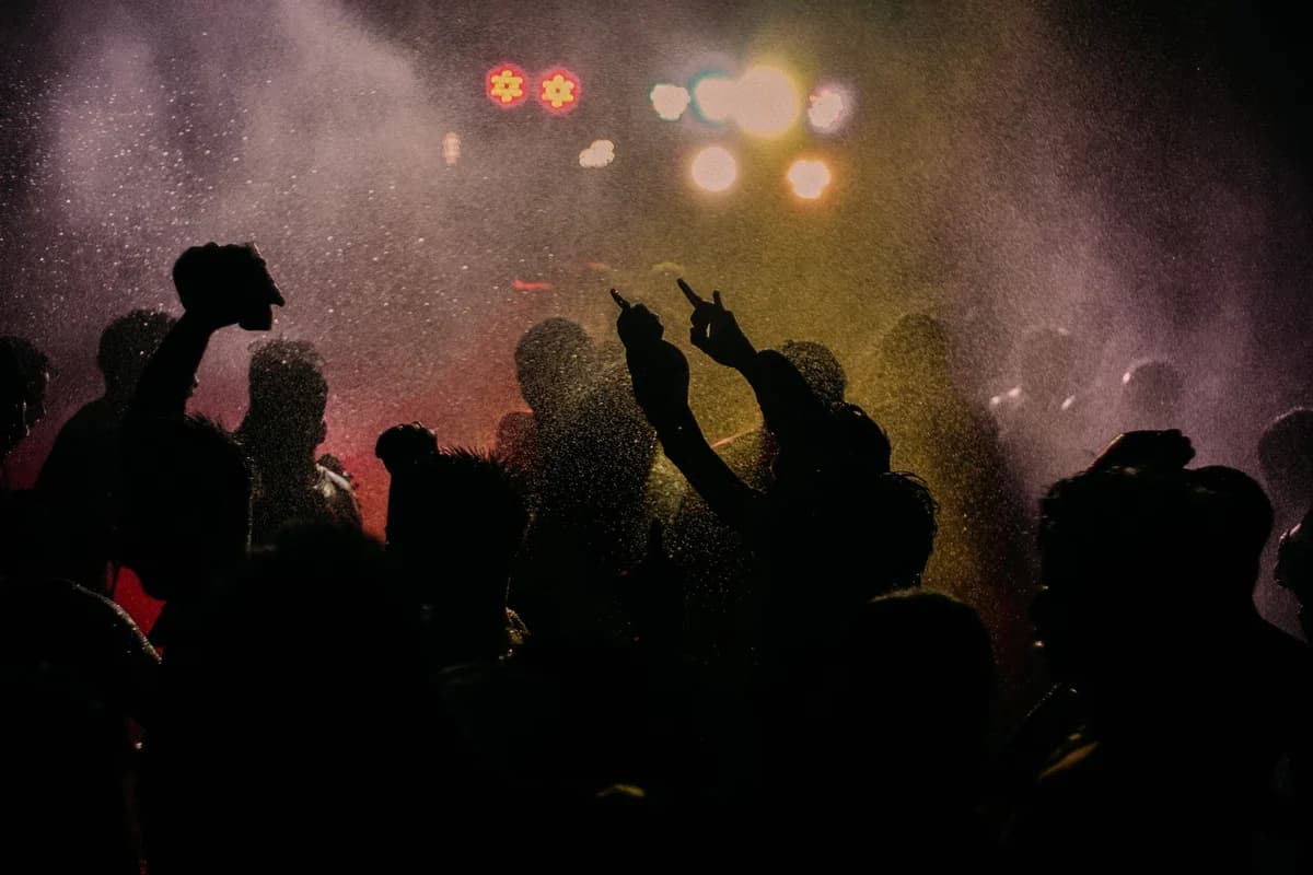 silhouettes of people at a party with bright lights and water mist