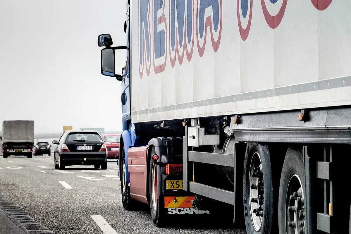 A blue truck and several cars driving on a cloudy highway near Copenhagen.