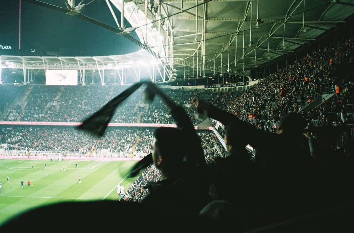 A crowded football stadium at night with fans cheering in the stands.
