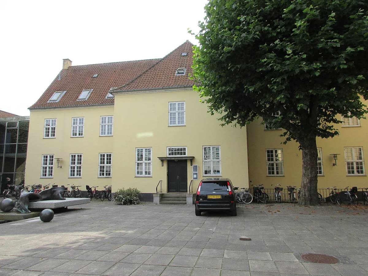 rear side of yellow building with car, tree and bicycles