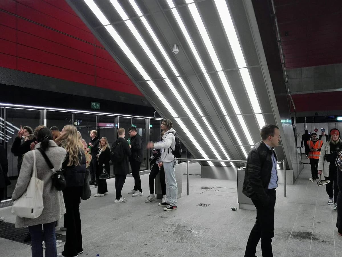People on a modern underground metro platform with bright lights.