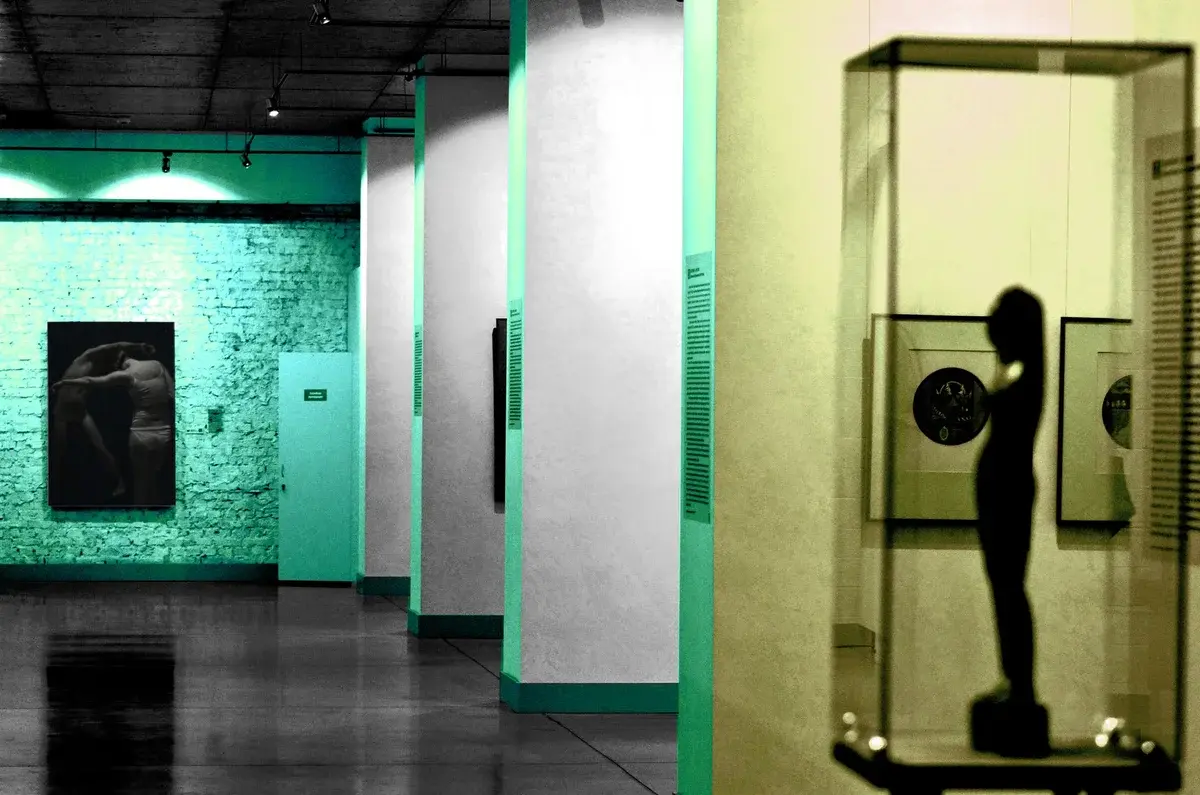 Contemporary art gallery interior with framed art on the walls and a sculpture in a glass case.