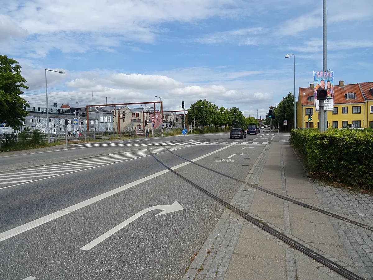 Railway tracks on street at Toldbodvej in Køge with buildings and cars