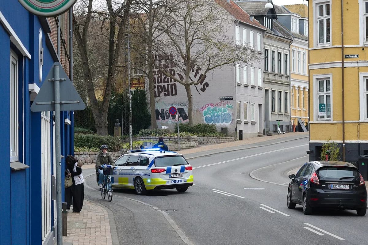 Police car blocking Nedergade street in Odense with people nearby
