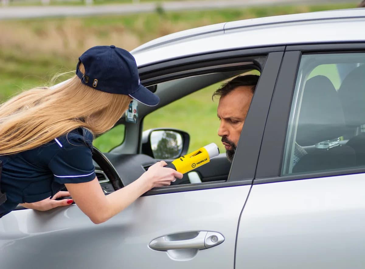 Officer giving breathalyzer test to driver in car