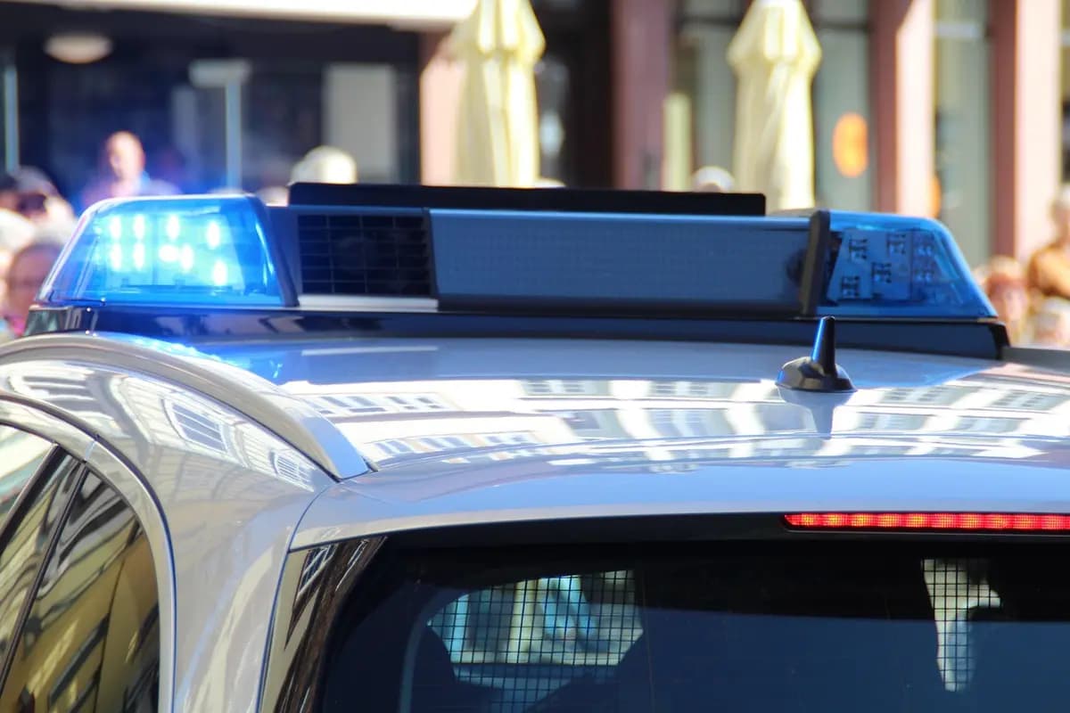 Police car with flashing blue emergency lights during the day