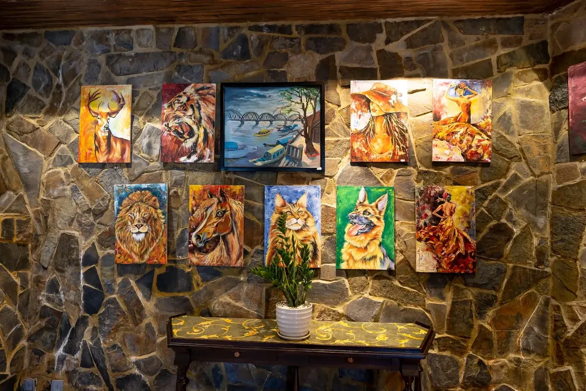 Colorful paintings of animals and a landscape displayed on a stone wall.