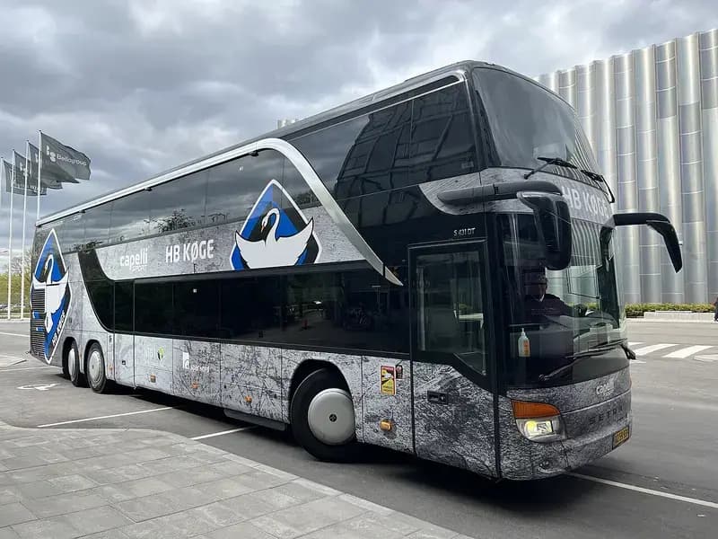 HB Køge team bus parked outside Bella Arena with club logo and sponsors