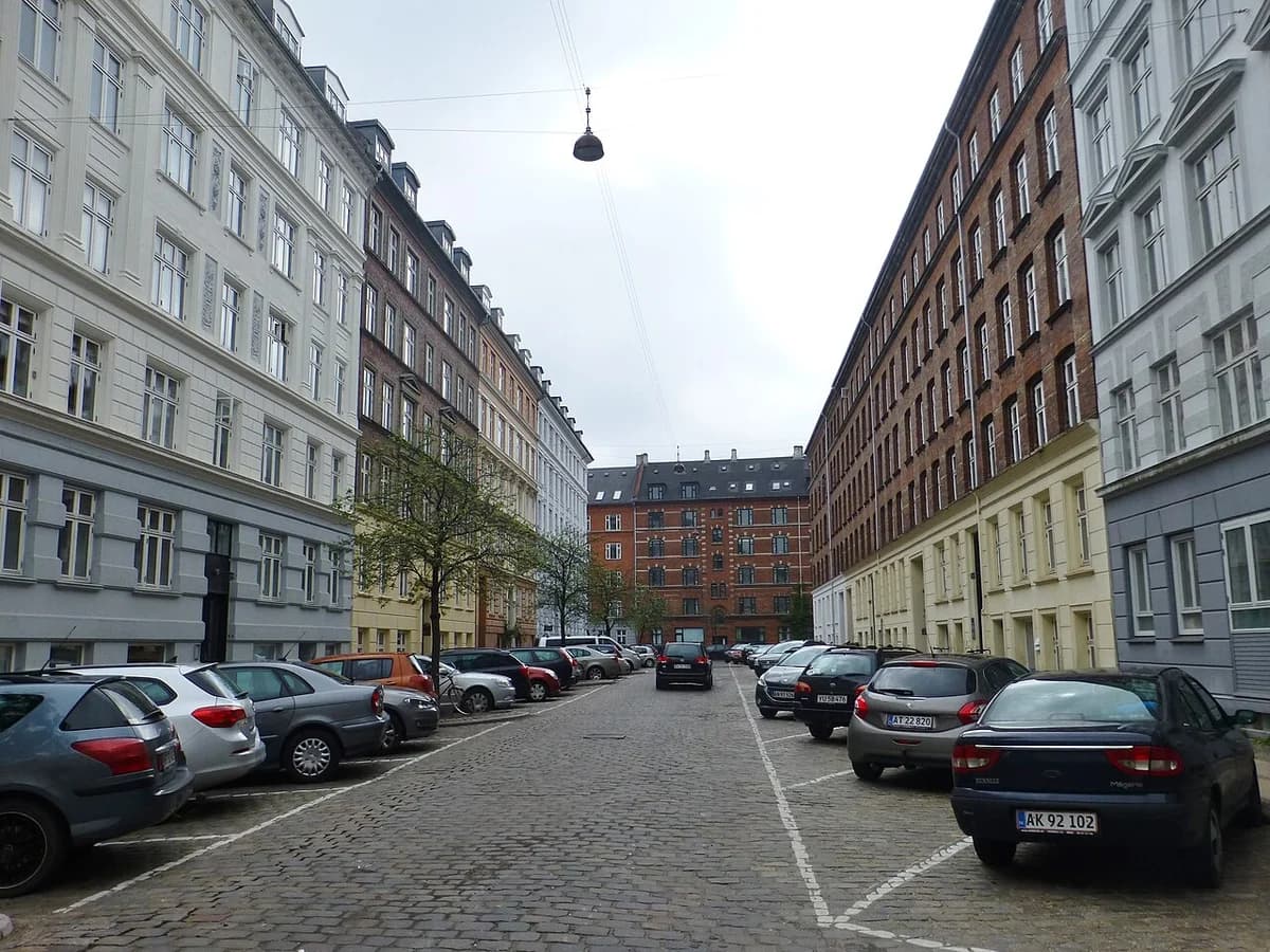 Cobbled street with parked cars and traditional buildings