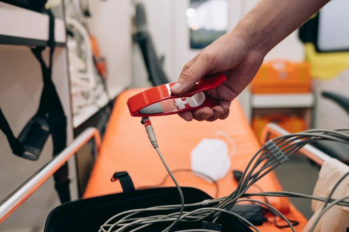 A paramedic holds a medical device inside an ambulance.