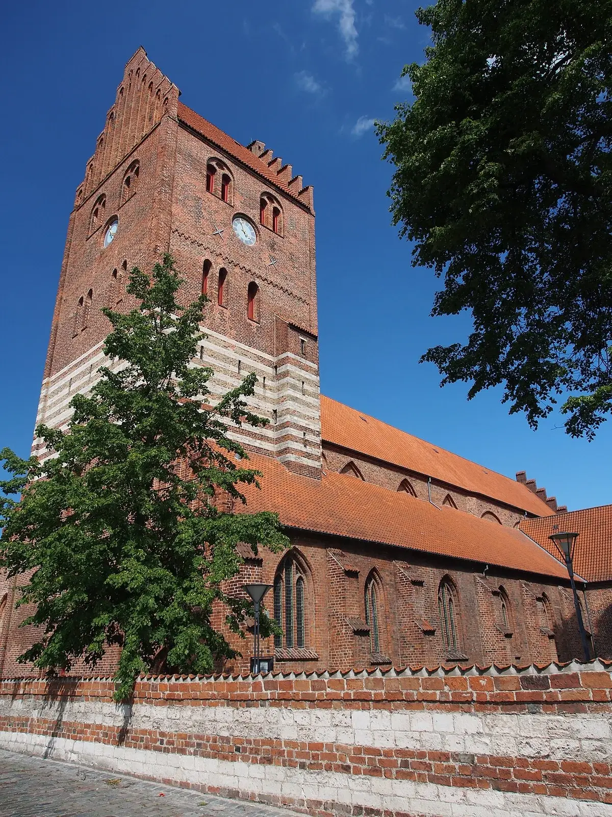 A brick church tower and nave in Køge, Denmark, viewed from below.