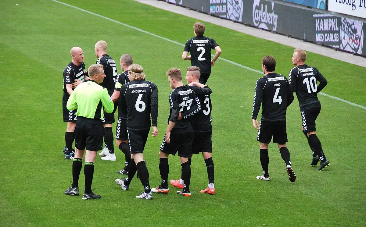 Soccer players from Akademisk Boldklub celebrate a goal on the field.