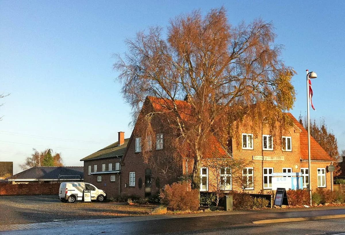 Exterior of a community hall in Bjæverskov with a Danish flag and parked van.