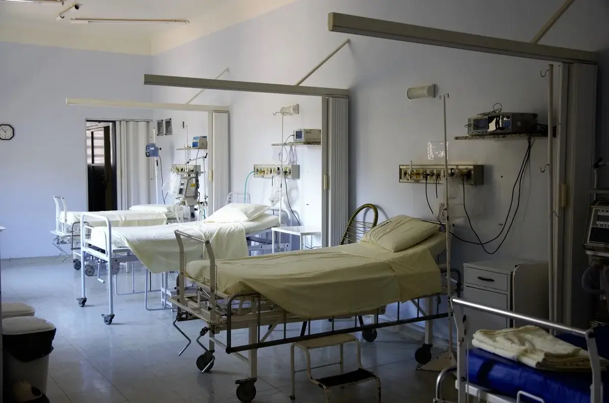 An empty hospital ward with several beds and medical equipment.
