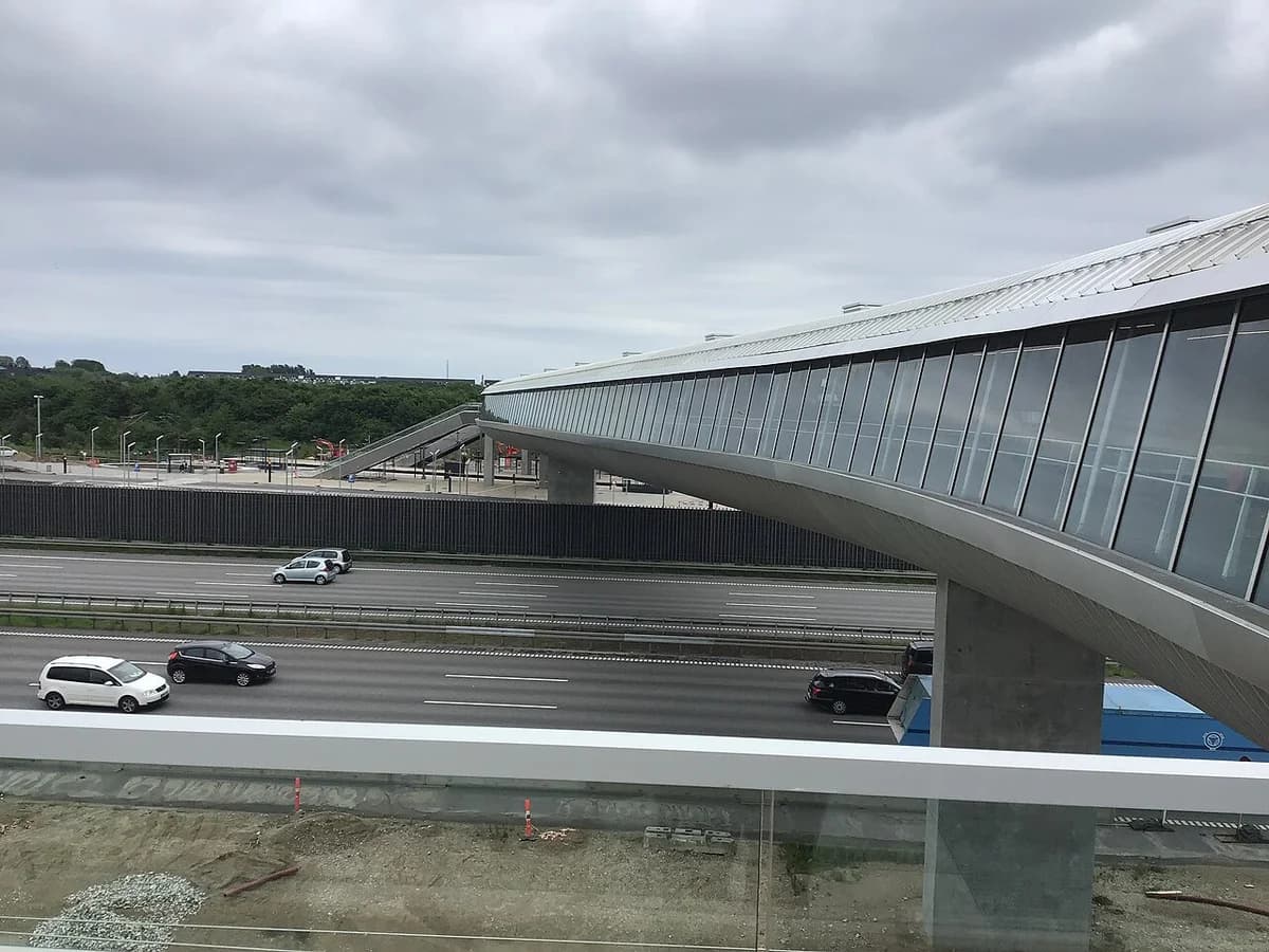 A modern station bridge crossing over a highway with cars below.