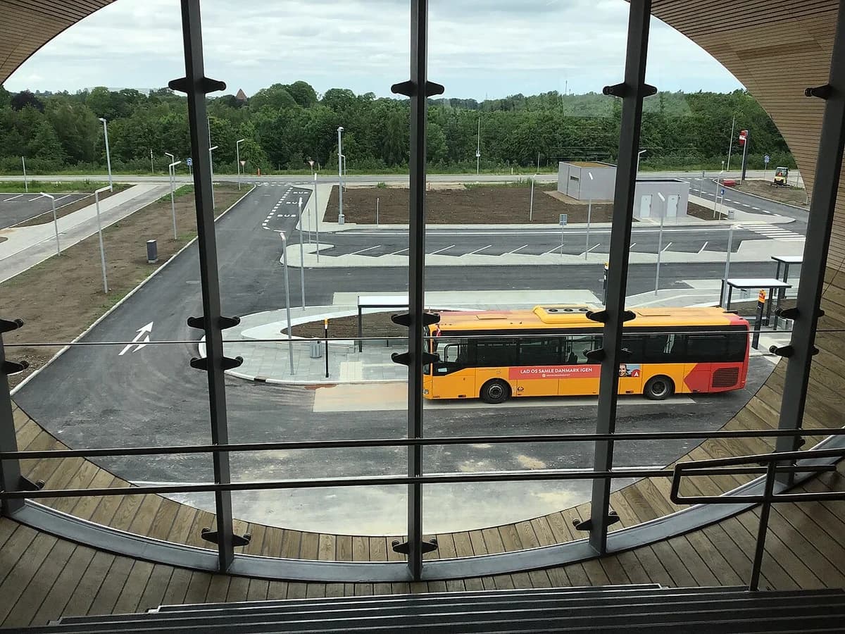 View of a bus terminal area from inside a building showing a yellow-red bus parked outside