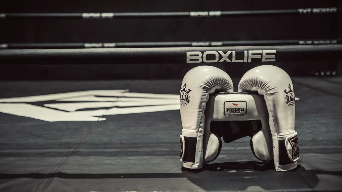 White boxing gloves sitting on a boxing ring canvas.