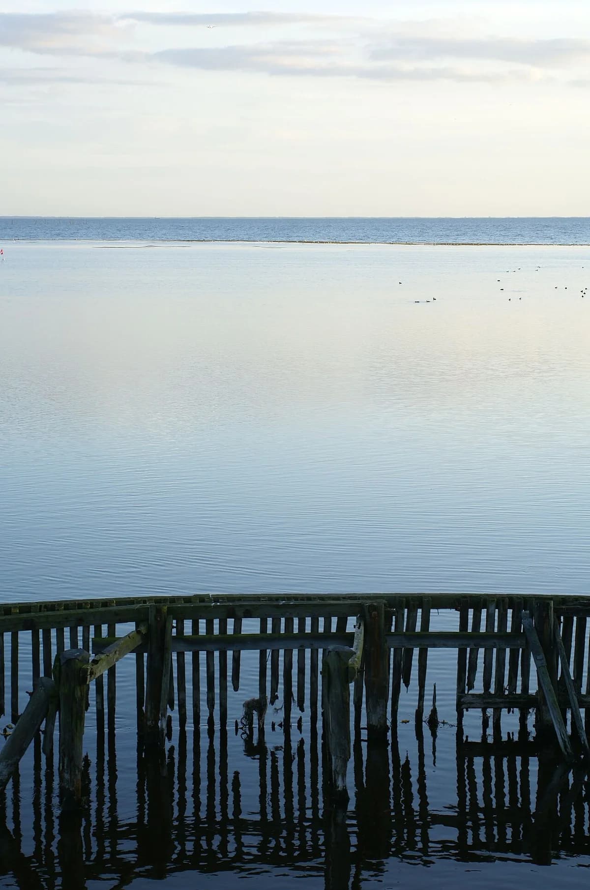 Calm coastal waters with an old wooden structure in the foreground.